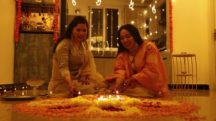 Indian women decorating house with lamps and flowers on the occasion of Diwali festival. India 