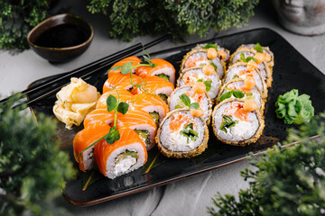 Tempura and philadelphia sushi rolls decorated with microgreens being served on black plate