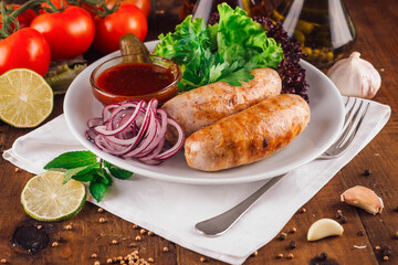 Two grilled sausages served on plate with salad and spices on wooden table