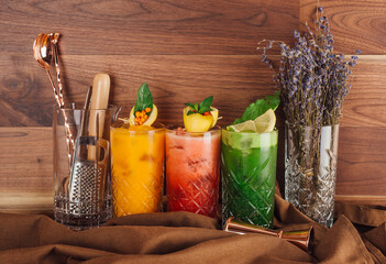 Three colorful cocktails standing on table with cocktail shaker and lavender