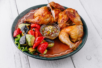 Roasted chicken with vegetables and sauce on rustic plate
