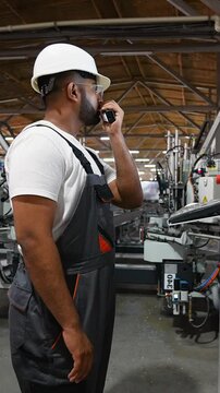 Industrial worker programmer sets up production line conveyor and gives commands via radio walkie talkie
