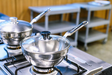 Close-up of Silver Cooking Pots on a Gas Stove, with Focus on the Pots in the Foreground and...