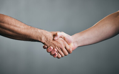People, fitness and handshake with greeting for teamwork, partnership or deal on a gray studio background. Closeup of men shaking hands in agreement, unity or meeting for workout challenge together