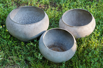 Outdated old bell-shaped metal pots different sizes on grass