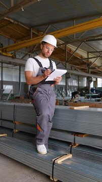Warehouse worker writes out the invoice before sending metal profile