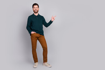 Photo of attractive cheerful handsome man wear stylish clothes recommend empty space isolated on gray color background