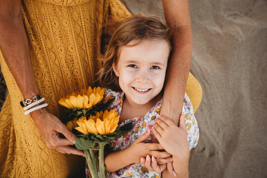 Girl lying on mom lap holding hands at beach in summer