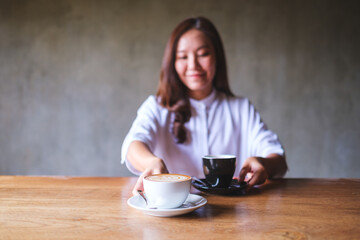 Portrait image of a young woman holding and serving two cups of coffee