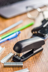Black office stapler on wooden table.