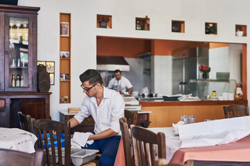 Restaurant, waiter and man with dishes for setting a table, cleaning and and check inventory. Fine dining, food industry and person with cutlery for dinner service, preparation and catering business