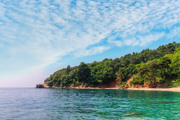 scenic summer landscape of beautiful sea shore with water vawes in bay, green forest on isle rock...