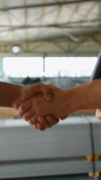 Handshake two diverse engineers on the background of a metal profile warehouse