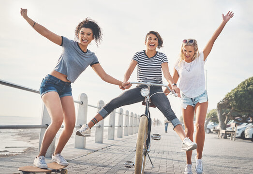 Cycling, friends and skateboard with women in summer for sports, fun and holiday break. Health, joy and wellness with group helping bike on promenade for relaxing, Miami travel and freedom together