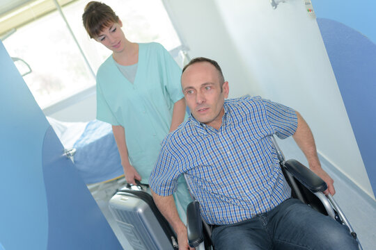 nuse and man in a wheelchair leaving hospital