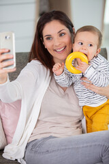 mother and baby taking selfie on sofa