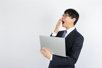 あくびをする寝不足の若いビジネスマン