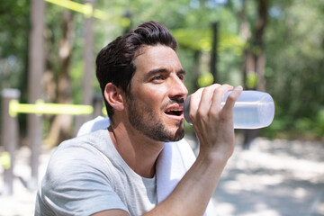 a young man drinking a bottle of water outdoors