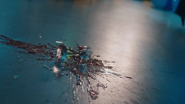 Glass with red wine shatters on the floor in slow motion, creating a dramatic splash