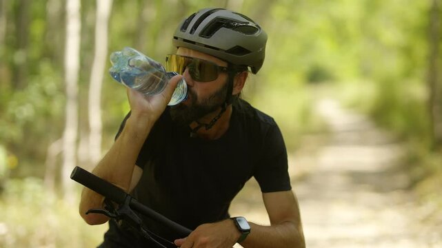 Cyclist quenching thirst in sunny forest pathway