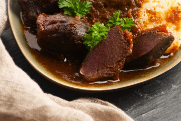 Stewed goose stomach.  Traditional Polish meat on a dark background.