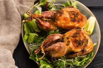 Baked tasty quails on ceramics plate with salad