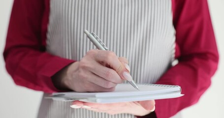Female waitress writes in notepad wearing apron
