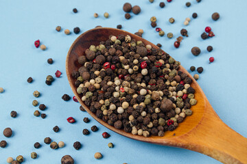 Mix of peppers on a wooden spoon on a blue background