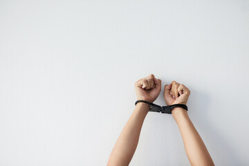 Hands, person and bound with handcuffs in studio for security, prisoner arrest and criminal hostage of struggle. Wrist, captivity and restricted with fist for violence, safety and white background