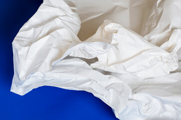 A large crumpled sheet of white paper on a blue background.
