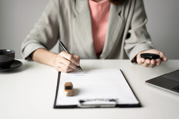 Car dealer businesswoman signing car insurance document or lease paper. Car insurance, loans and Car rentals concept