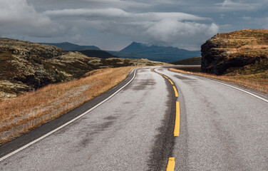 Road leading throught Norvegian severe Tundra nature close-up asphalt view. Picturesque northern Norway landscape and modern highway construction shot. Rondane National Park, Norway.