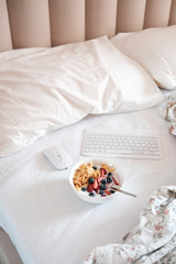 Indulging in a Cozy Breakfast in Bed while Surrounded by Technology and Fresh Fruits