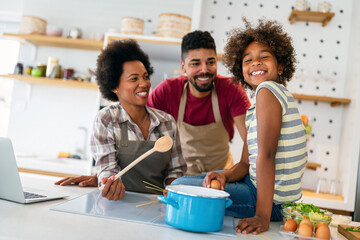 Happy african american family preparing healthy food in kitchen, having fun together on weekend