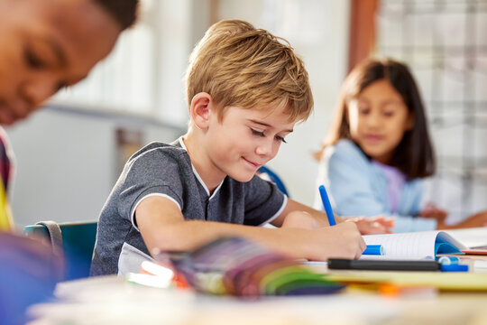 Elementary school boy writing on notebook at school