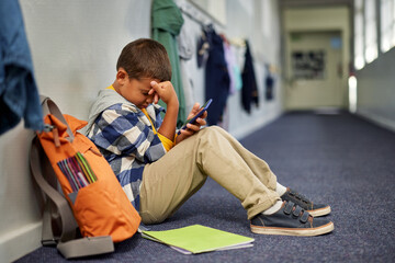 Depressed school boy being cyber bullied