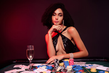 Photo of wealthy woman sit casino table with many chips dollars cards drink cahmpagne over red neon dark background