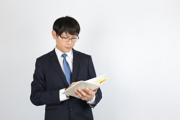 ノートを見て考える男性ビジネスマン