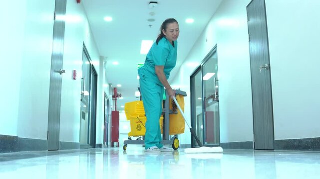 A uniformed cleaner carefully mops the epoxy floor in the patient room, making sure the hall floor is hygienically clean.