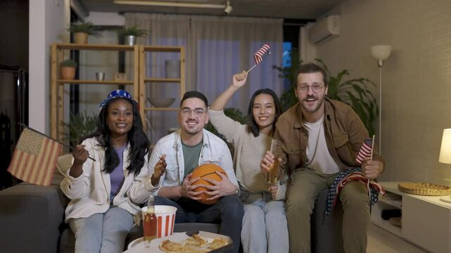 Multiracial group of friends watching basketball game, drinking beer and cheering.