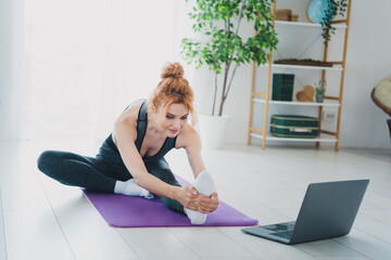 Photo of active charming lovely woman wearing activewear watching video doing stretch exercises from home indoors