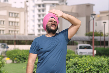 Sikh Indian Man Looking at Sun and Covering Face with Hand