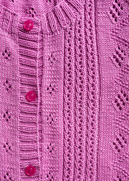 Handmade pink fuchsia knitting cotton texture background with knitted lace pattern. Part of cardigan with buttons. Top view of knitting clothes