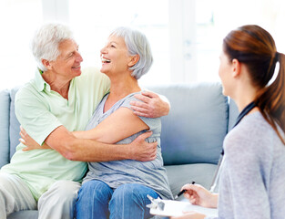Obraz premium Senior couple, happy and embrace on couch in nursing home with good news, doctor or positive results. Old partners, hug or laugh with nurse or carer in retirement centre for diagnosis, test or health