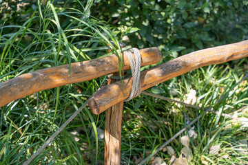 Wooden fence secured with rope. The fence is surrounded by green grass