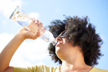 Man, drinking and water with blue sky outdoor for concert, event or wellness with sunglasses and...