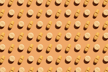 Pattern of different pills on orange background, creating a visually striking geometric layout. Creative pills concept