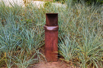 Obraz premium Square metal trash can. Rectangular rusty trash can stands on the ground outdoors