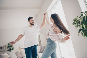 Photo of two idyllic partners hold hands dancing modern bright interior weekend flat indoors