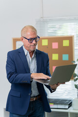 handsome business man in an elegant blue suit working with laptop on the table in the office